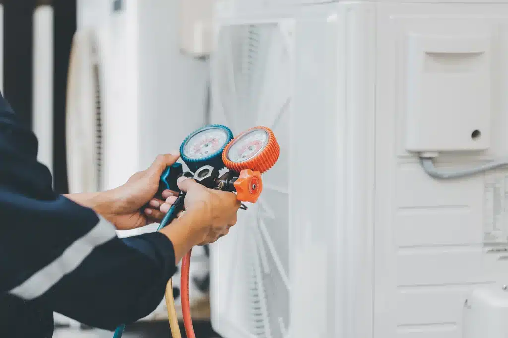 Technician using refrigerant pressure gauges during an air conditioner diagnostic