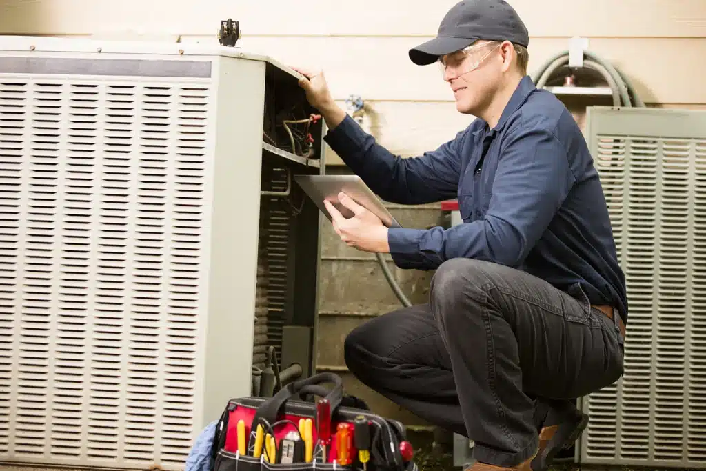 Technician performing an emergency air conditioning repair using a diagnostic tablet