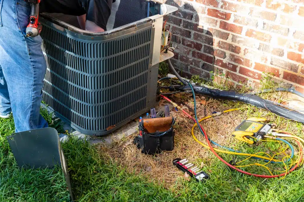 Technician performing an annual air conditioning tune-up on an outdoor unit