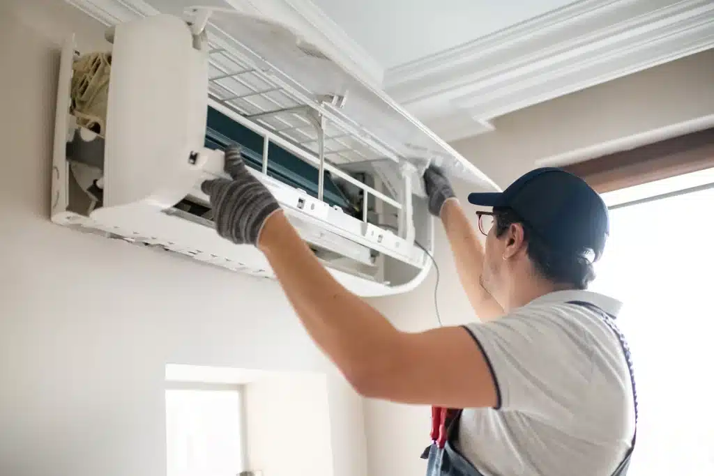 Technician repairing an indoor ductless mini-split air conditioning unit