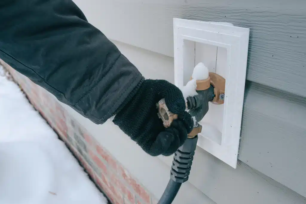 Hand thawing a frozen exterior pipe covered in frost