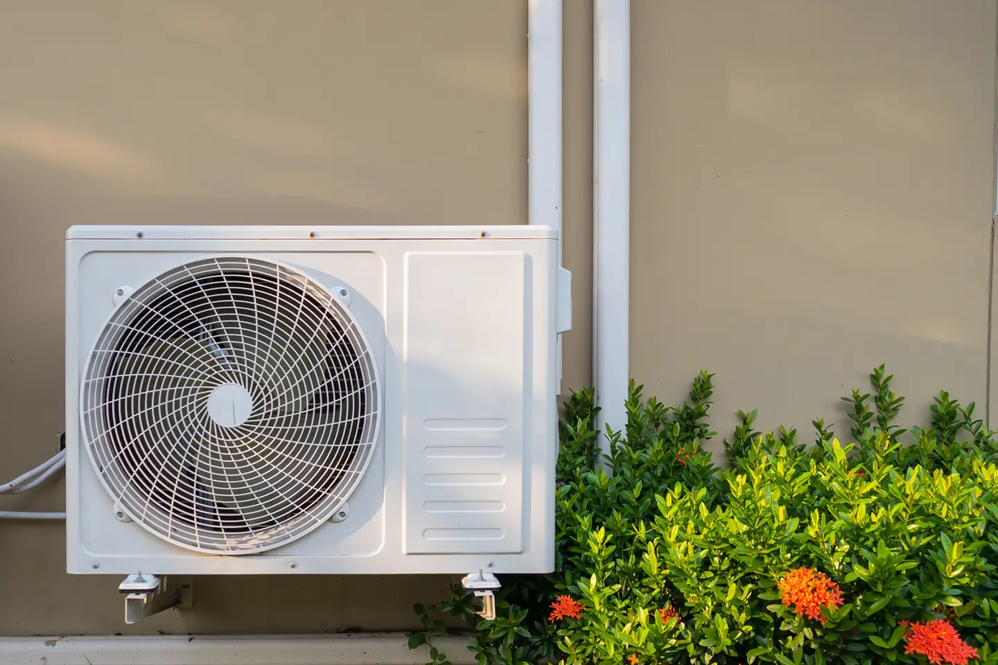 Outdoor air conditioning unit installed next to spring landscaping, illustrating the best season to book