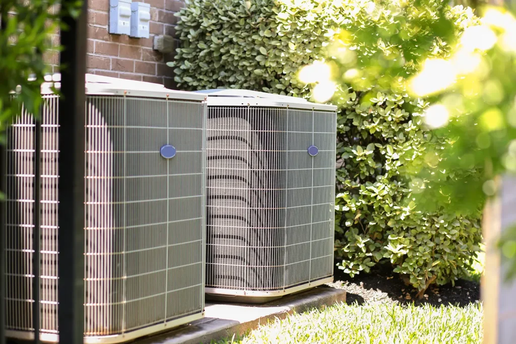 Two outdoor central air conditioning condenser units installed beside a Calgary home