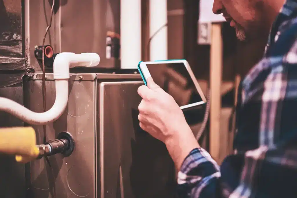 Technician using a tablet to log combustion analysis and diagnostic results during a furnace inspection