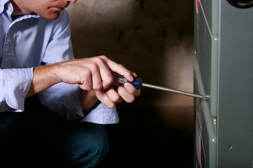 Technician servicing a furnace panel, illustrating the best time to book a fall tune-up