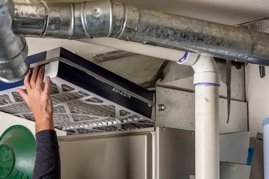 Technician replacing a furnace filter before the start of the winter heating season