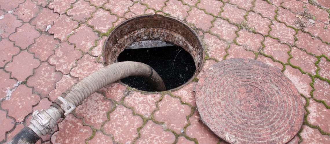 man pumping sewage from the drain hole.